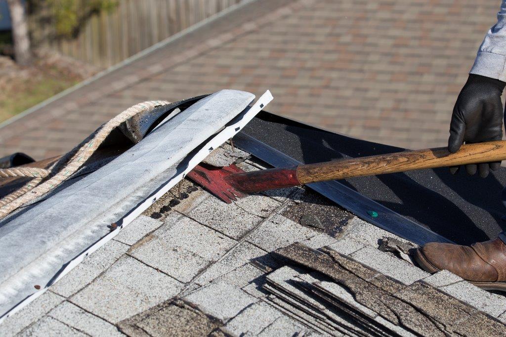 employee removing roofing shingles